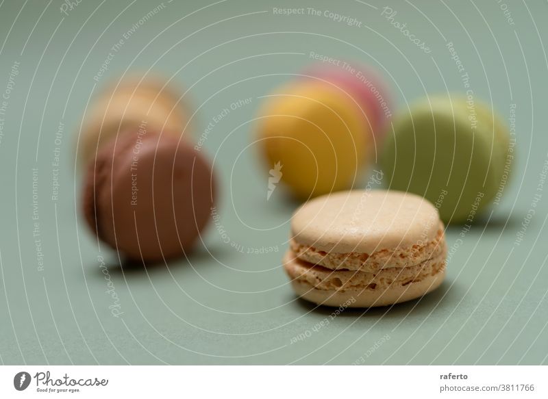 Colored tasty macaroons over a green background. In A Row Orange Purple Studio Shot appetizing arranged baked goods baking black background bright chewy color