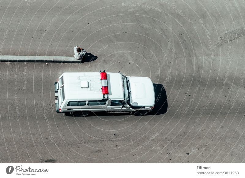 ambulace passing by and a man sitting in the middle of the street Ambulance road Man top view