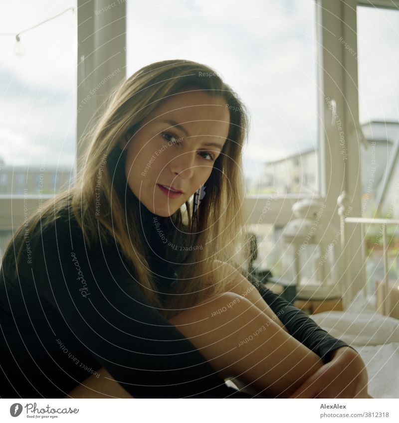 Analog, close up portrait of a young woman sitting on a bed and looking into the camera Woman 18 - 30 years pretty fit Slim smart kind Pleasant Attractive