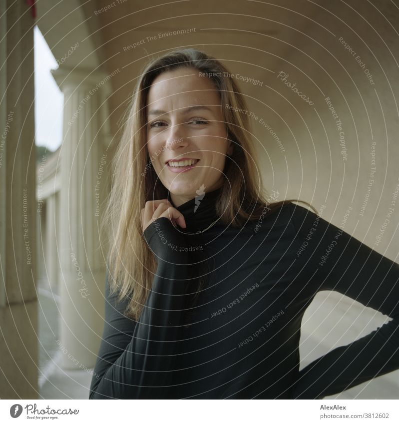 Close portrait of a smiling young woman with dimples in a colonnade Woman 18 - 30 years pretty fit Slim smart kind Pleasant Attractive Brunette Long-haired