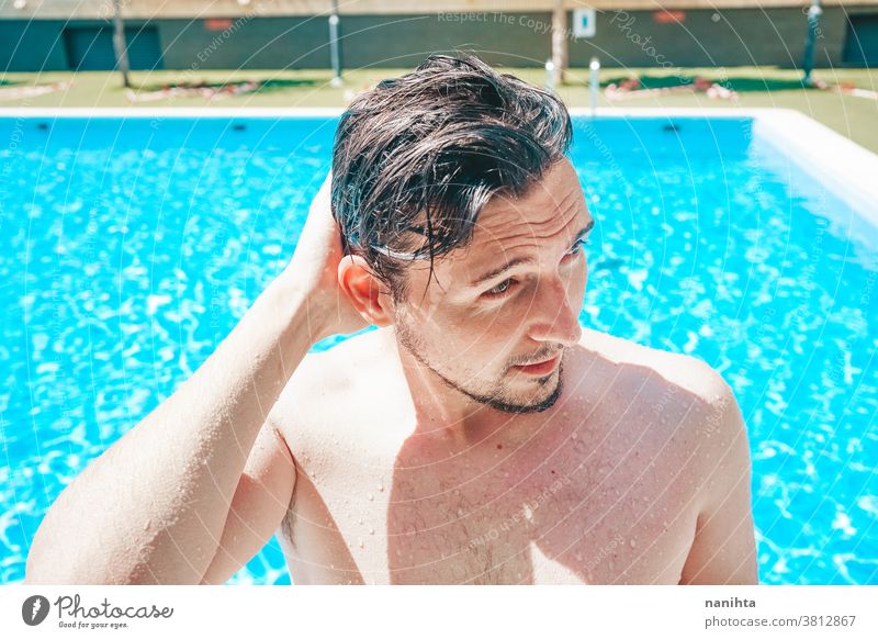 Young handsome man posing near a pool attractive sexy male swimming pool summer skin beard guy smile tan blue water party portrait portraiture real people cool