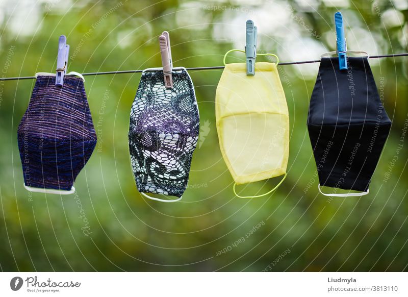 Coronavirus concept. Different types of handmade protective facial masks hanging on a rope outdoors air background care childish children clean clothes