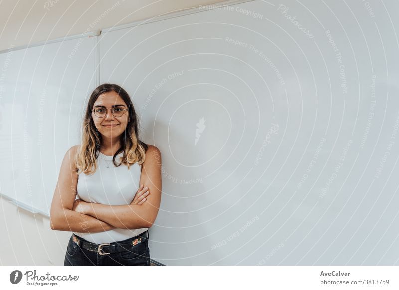 Young woman and worker in front of a board crossing hands and looking to camera school university mathematics classroom college student happy study teacher