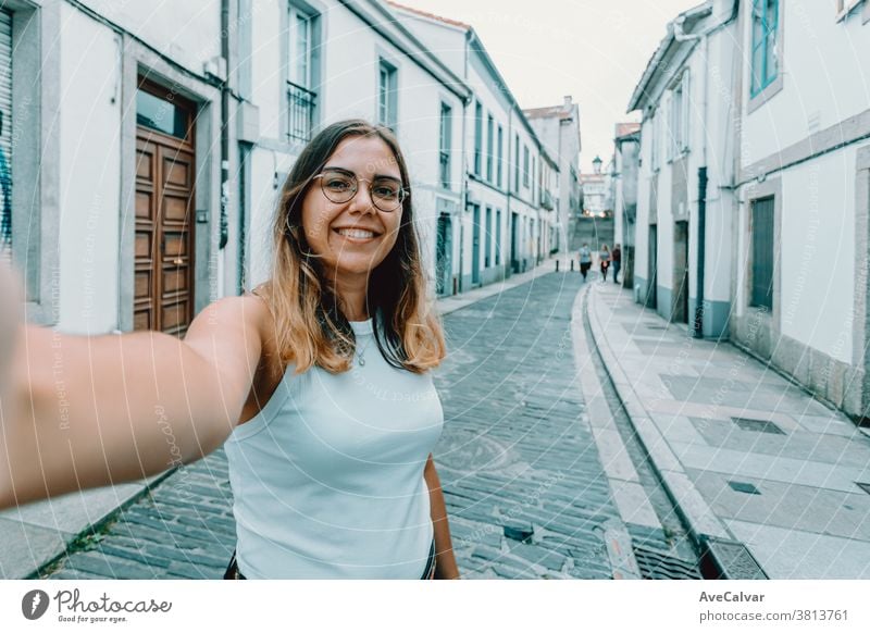 Young woman with glasses taking a selfie on a old spanish street pretty smart-phone trendy joyful brunette outdoors modern beauty style casual attire fun female