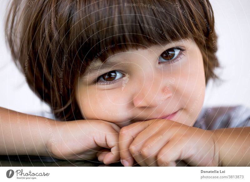 Close up little boy portrait 3-4 years beautiful brown eyes brown hair calm childhood cute face family happy horizontal long hair look at camera male one