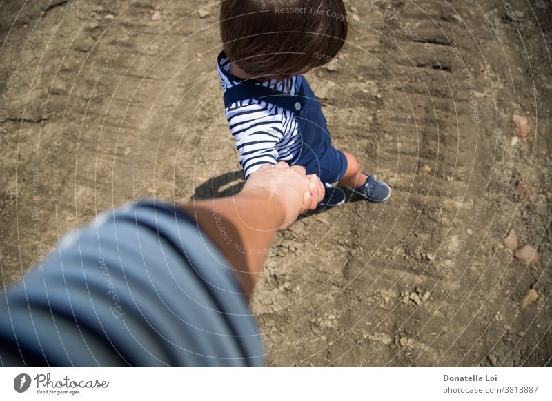 mother and son holding hands accompany casual childhood from above ground little boy stripes summer together walking