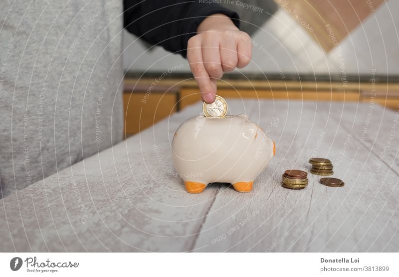 Child putting a coin into piggy bank at home banking budget cash caucasian ceramics child childhood coins concept crisis debt deposit earn economize economy