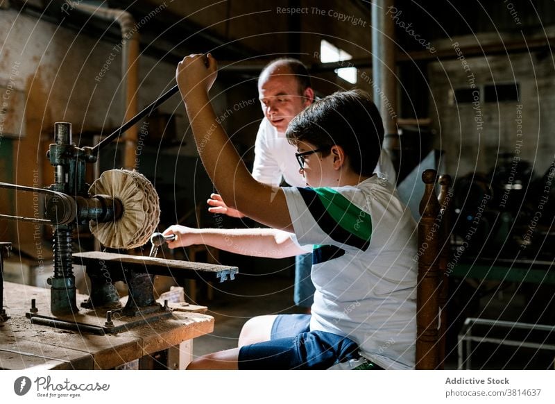 Boy helping father in grungy workshop grunge son polish together boy helper focus concentrate busy press handicraft create manual serious hobby mechanism old