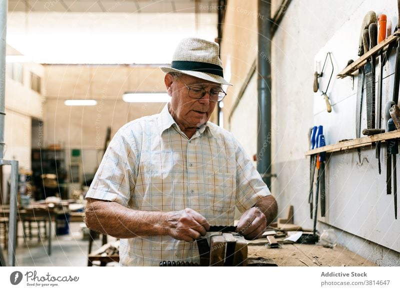 Senior male woodworker working in garage grind carpentry workshop man carpenter fold fan handmade wooden occupation skill tool messy artisan craft