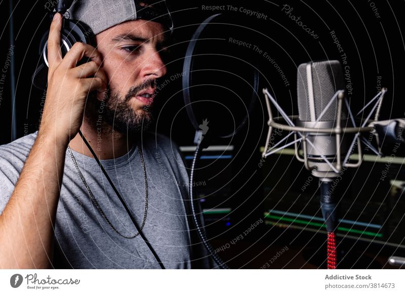 Man in recording studio microphone sing man artist hat singer headphones acoustic foam male sound proof song room music musician modern contemporary gadget cap