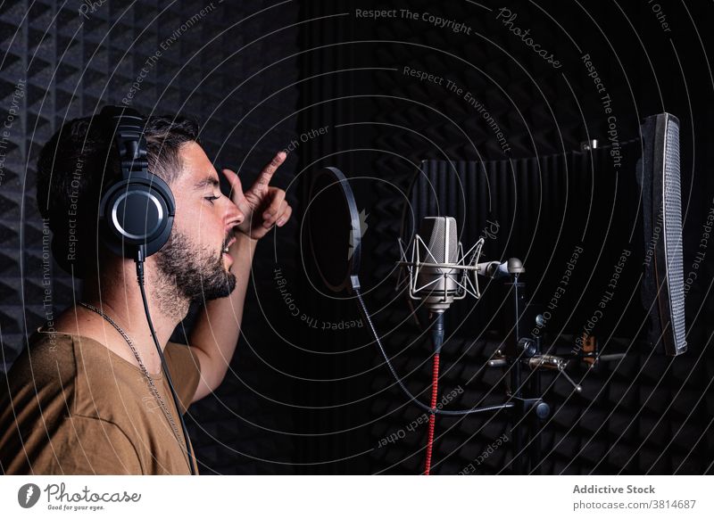 Man in recording studio microphone sing man artist singer headphones acoustic foam male sound proof song room music musician modern contemporary gadget listen