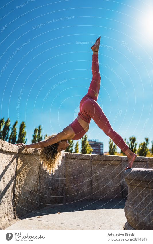 Flexible woman doing yoga pose on stone border downward facing dog eka pada adho mukha svanasana flexible practice balance position slim female wellness harmony