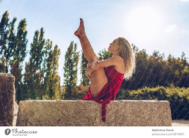 Woman in seated balancing pose practicing yoga in park woman flexible stretch balance boat urdhva mukha pascimottanasana practice position slim female wellness