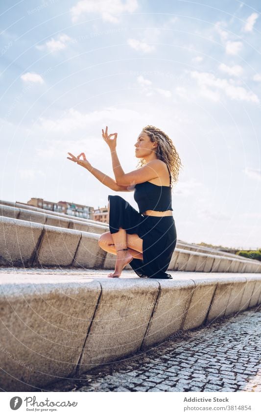 Focused woman practicing  yoga meditation on steps meditate toe stand mudra asana padangusthasana balance zen focus flexible pose practice position female