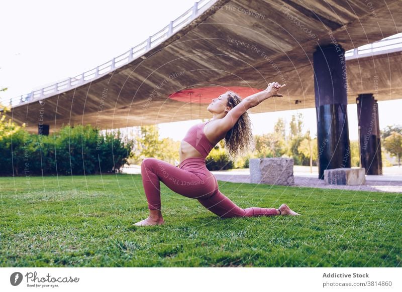 Focused woman practicing yoga in park asana flexible pose practice balance position slim female wellness harmony wellbeing activity concentrate vitality