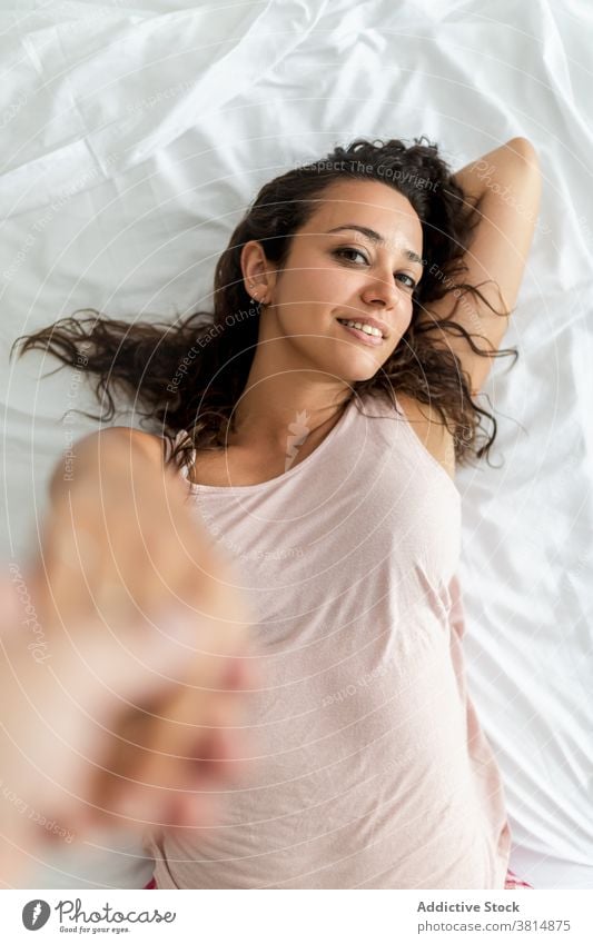 Tender woman holding hand of boyfriend in bedroom couple holding hands girlfriend tranquil charming soft relax relationship lying home rest tender calm pleasure