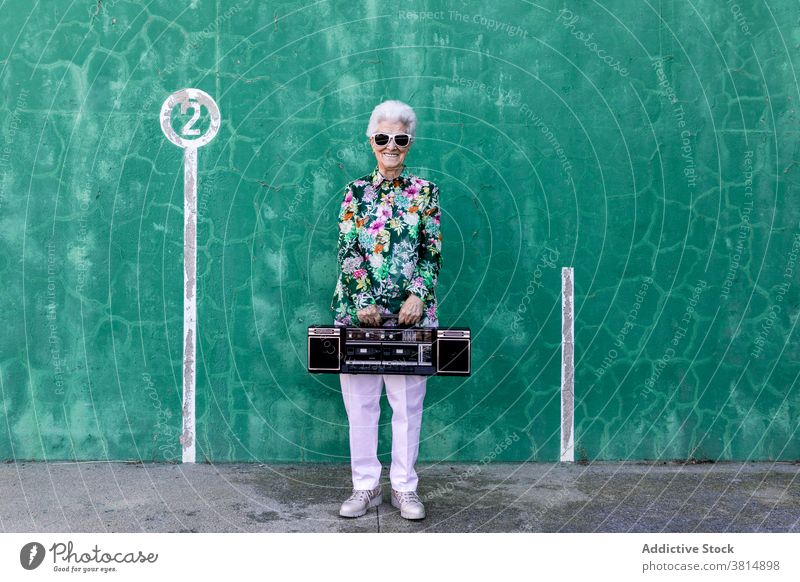 Senior woman with record player standing near wall senior music style elderly listen sound active female trendy lifestyle urban aged old device audio vintage