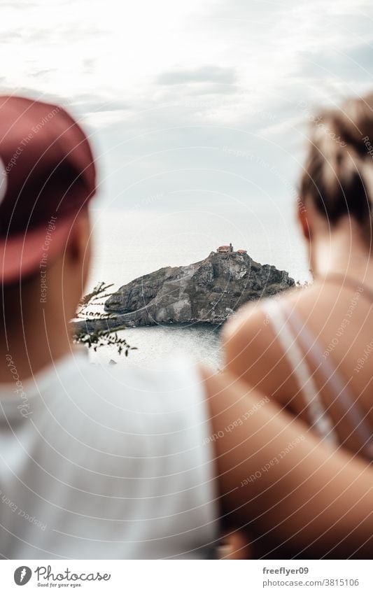 Young couple contemplating Gaztelugatxe Island tourists tourism visiting sightseeing sightseers romantic island vizcaya spain bermeo X century copy space travel