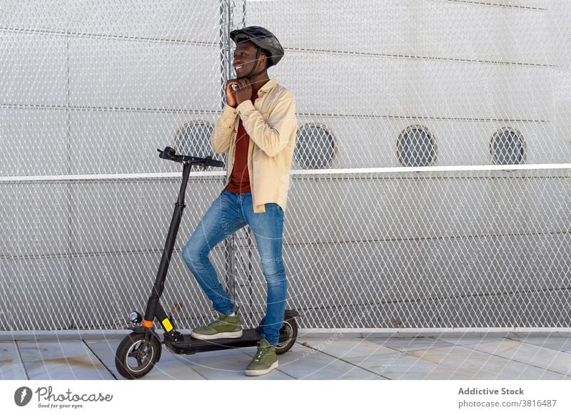 Smiling man with helmet near scooter on street electric city put on ready ride protect cheerful male ethnic black african american transport contemporary casual