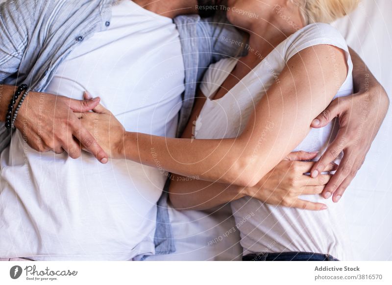 Anonymous gentle couple hugging on bed at home lying cuddle tender relationship love together touch affection happy rest casual soft embrace comfort romantic