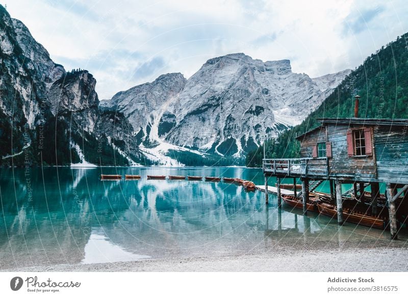 Wooden house and boats on lake in mountains turquoise water color wooden float reflection smooth surface calm clear shore scenery majestic morning light nature