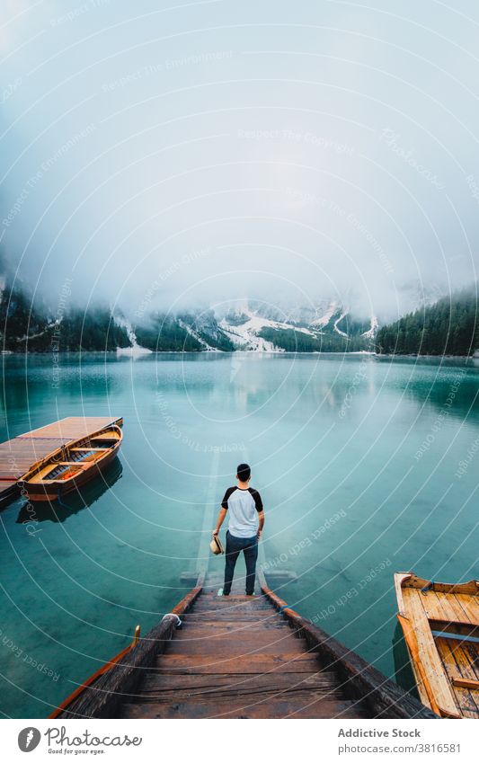 Traveling man on wooden pier near lake turquoise mountain travel adventure wanderlust landscape water male amazing traveler quay scenery vacation trip holiday