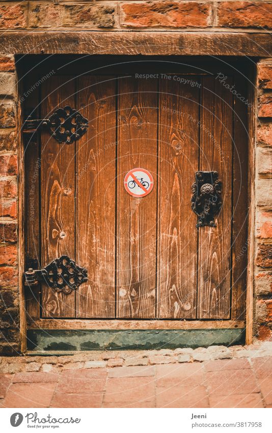 Small cute wooden door with old decorated metal fittings - on the door a prohibition sign "bicycles not allowed to be parked Wooden door door fitting