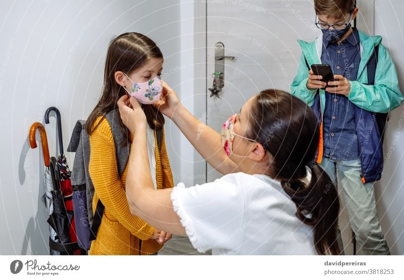 Mother putting the mask on her daughter mother preparing face mask go to school covid-19 coronavirus protective mask correctly fitting mask reusable cloth mask