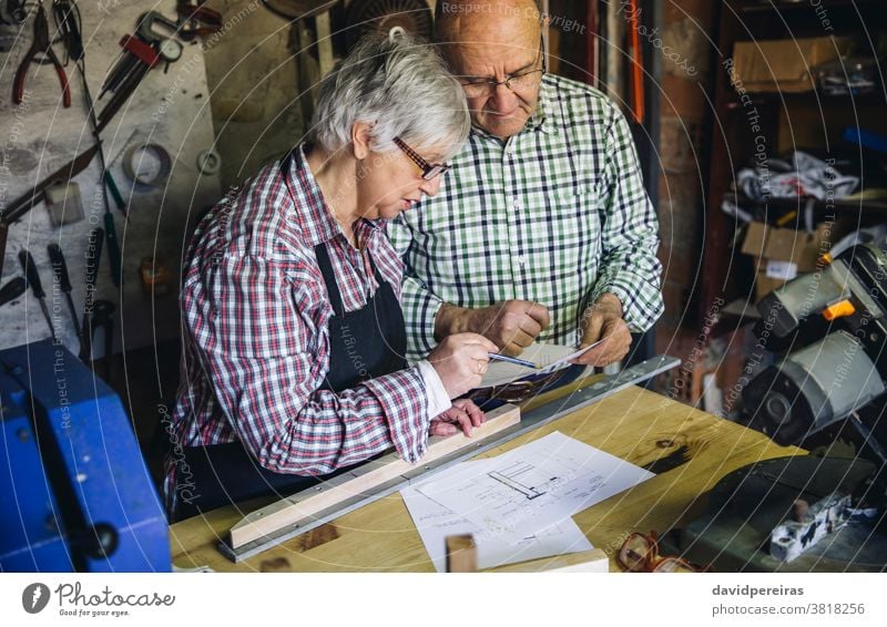 Senior couple in a carpentry carpenter senior looking plans working together workshop wood mature designing business carpentry shop caucasian home retirement