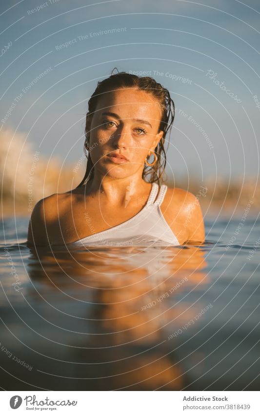 Young woman in sea water in summer wet hair sunset ocean enjoy weekend vacation carefree rest holiday nature evening dusk smile idyllic recreation tourism trip