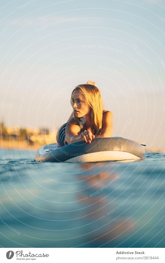 Serene woman on surfboard in sea lying relax sunset slim swimsuit water wave female sky recreation ocean summer swimwear rest weekend peaceful holiday calm