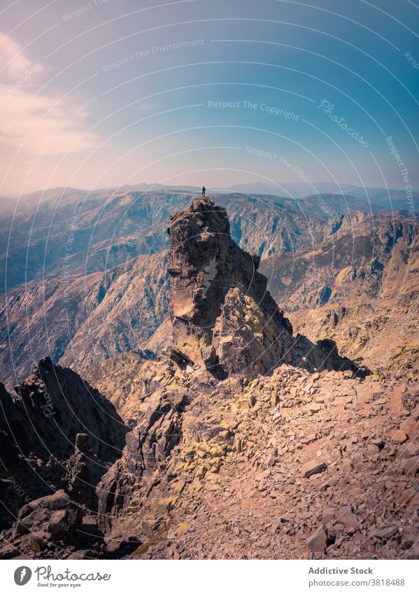 Unrecognizable tourist on rough rock under cloudy sky traveler admire ridge highland nature wanderlust explore blue sky breathtaking mountain journey