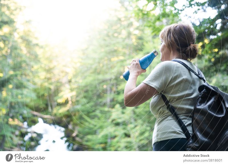 Female tourist drinking from water bottle near rapid river in forest traveler woman vacation creek valley rough slope brook Uelhs deth Joeu Val d'Aran Lleida