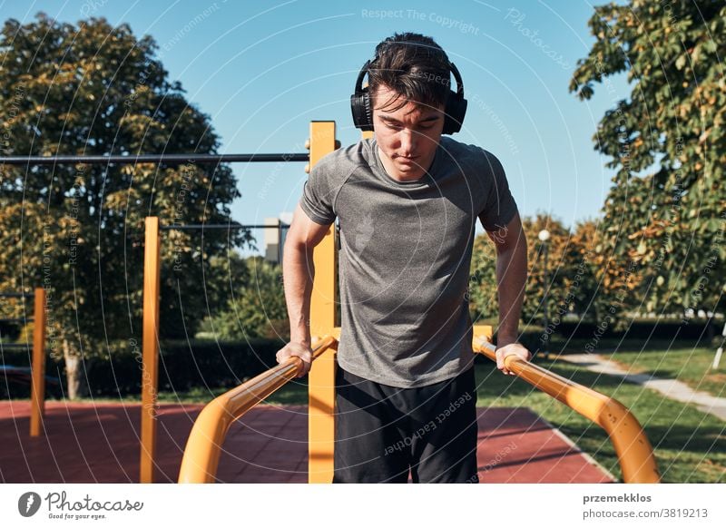 Young man doing dips on parallel bars during his workout in a modern calisthenics street workout park care caucasian health lifestyle male one outdoors person