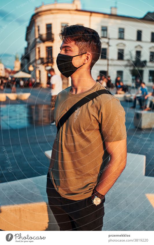 Young man standing in the city center wearing the face mask to avoid virus infection caucasian conversation covid-19 lifestyle outbreak outdoors pandemic