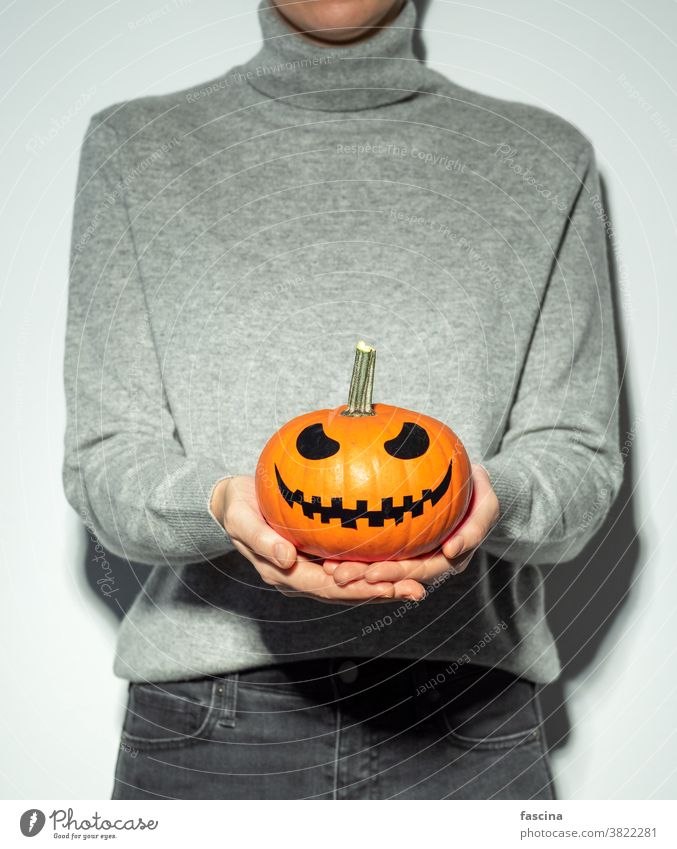 Minimalistic halloween concept pumpkin jack-o-lantern unrecognizable holiday trick-or-treat girl fashion carved conceptual food party produce squash vegetable