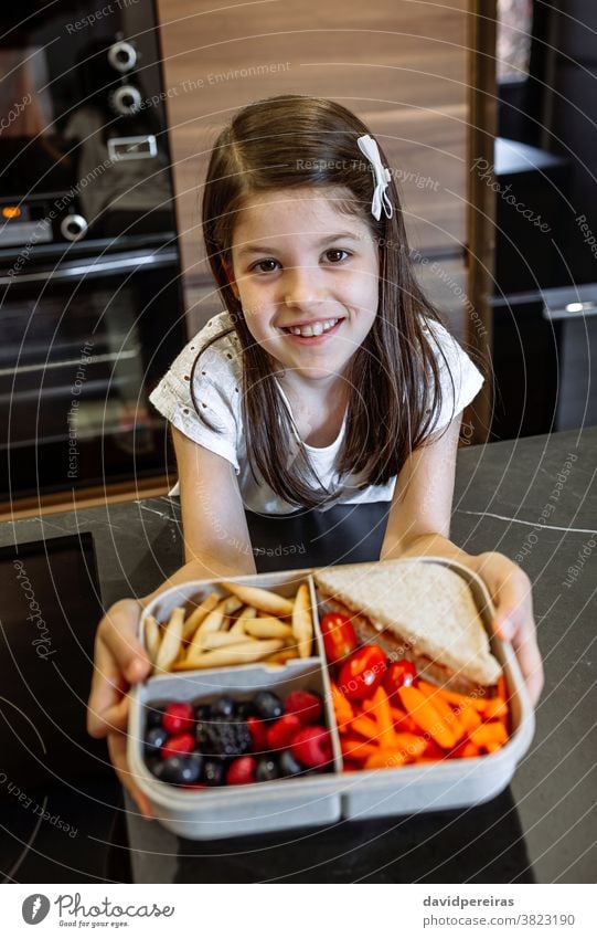 Happy girl showing lunch box filled with healthy food happy school vegetarian healthy snack delicious fruit take-away hands holding lunch box compartments