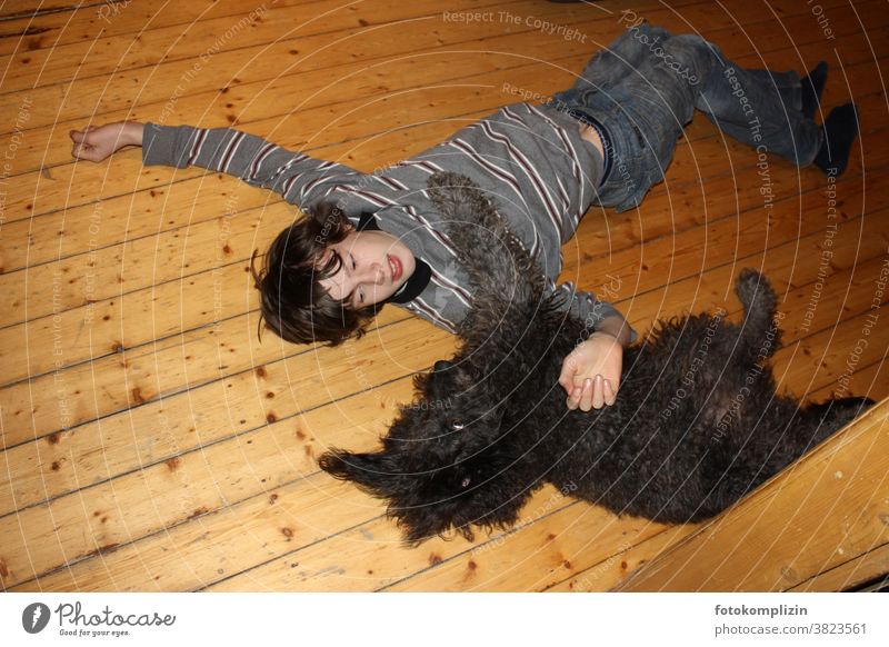 Boy and dog lying side by side on a floorboard Cuddling Pet Touch Friendship tie dog love Humans and animals Animal Communication Man and dog Love of animals