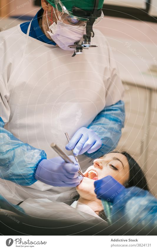 Unrecognizable dentist examining teeth of patient in clinic stomatology examine process oral procedure tool uniform nurse using medical equipment health care