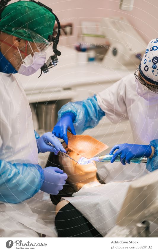 Unrecognizable dentist examining teeth of patient in clinic stomatology examine process oral procedure tool uniform nurse using medical equipment health care