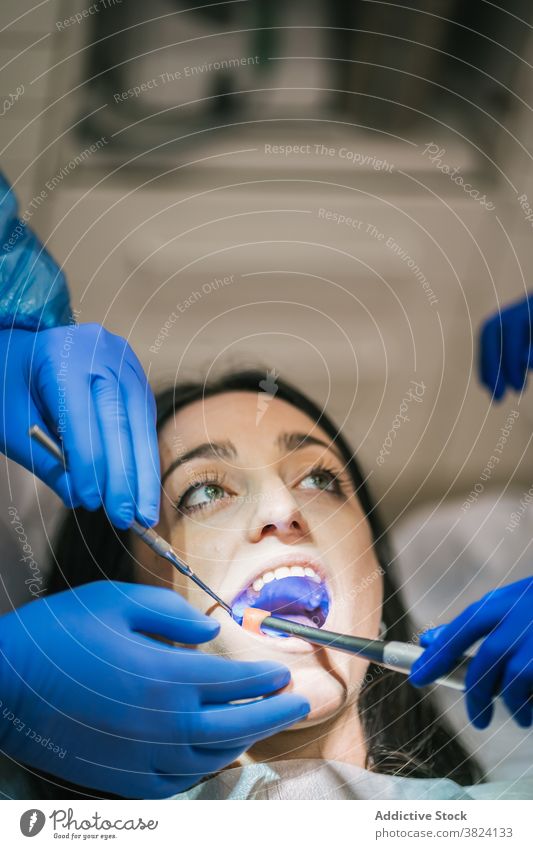 Unrecognizable dentist examining teeth of patient in clinic stomatology examine process oral procedure tool uniform nurse using medical equipment health care