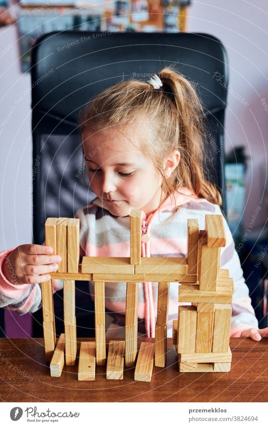 Little girl preschooler playing with wooden blocks toy building a house activity brick child childhood concept construction creativity education fun funny game