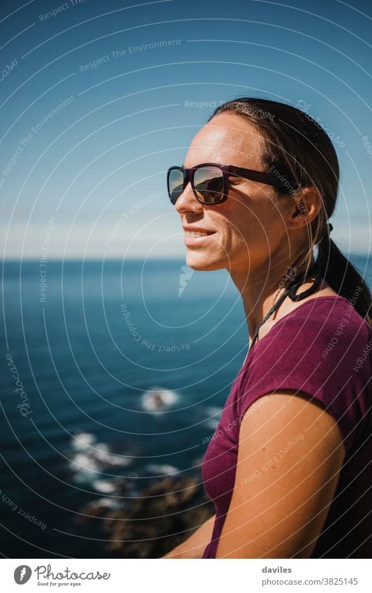 White woman with sunglases enjoying views from a cliff in atlantic ocean. seaside europe north european spain asturias brights face close up portrait blue sky