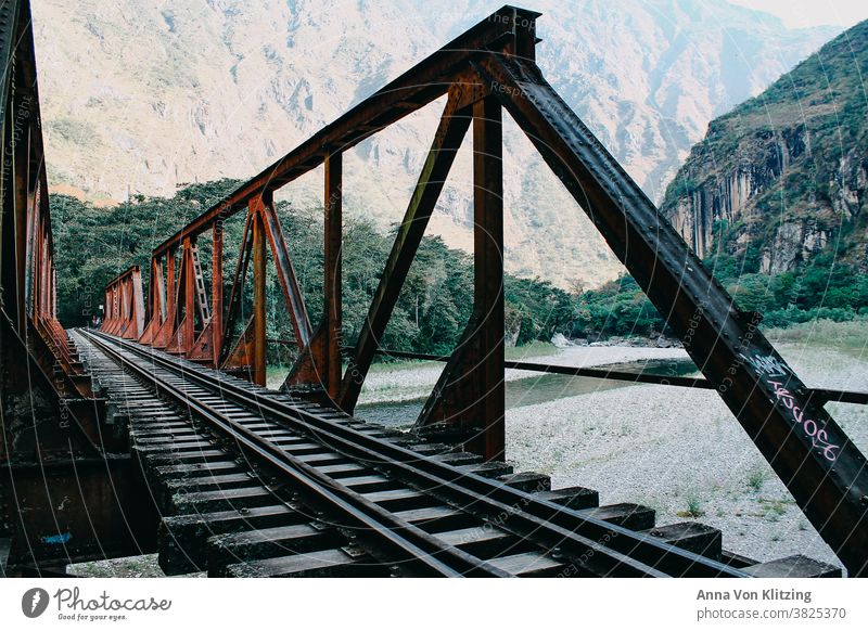 Railway bridge Peru Bridge Steel rails Red Canyon River mountains tropics Traverse trees Forest Virgin forest Hiking travel Machu Pichu River bank South America