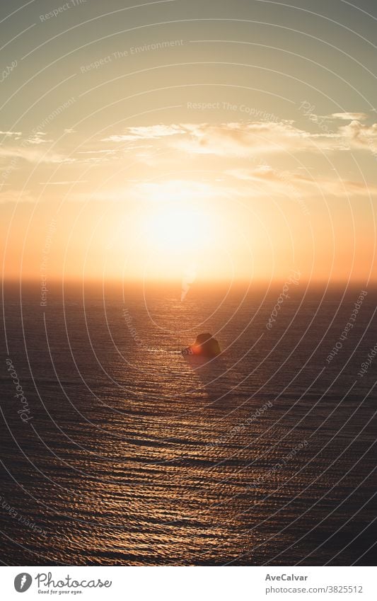 A massive sunset over a lonely rock in the middle of the ocean seascape illuminated outdoors sunlight nature sunrise scenics tranquil scene nobody view