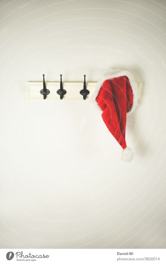 Santa cap hangs on a coat hook / wall coat rack Christmas & Advent Santa Claus hat Clothes peg Wall coat rack christmas time Anticipation christmas eve Cute