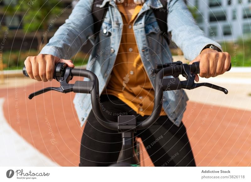 Crop man riding modern bicycle in city ride bike street transport commute male ethnic contemporary activity urban move summer town vehicle road motion guy