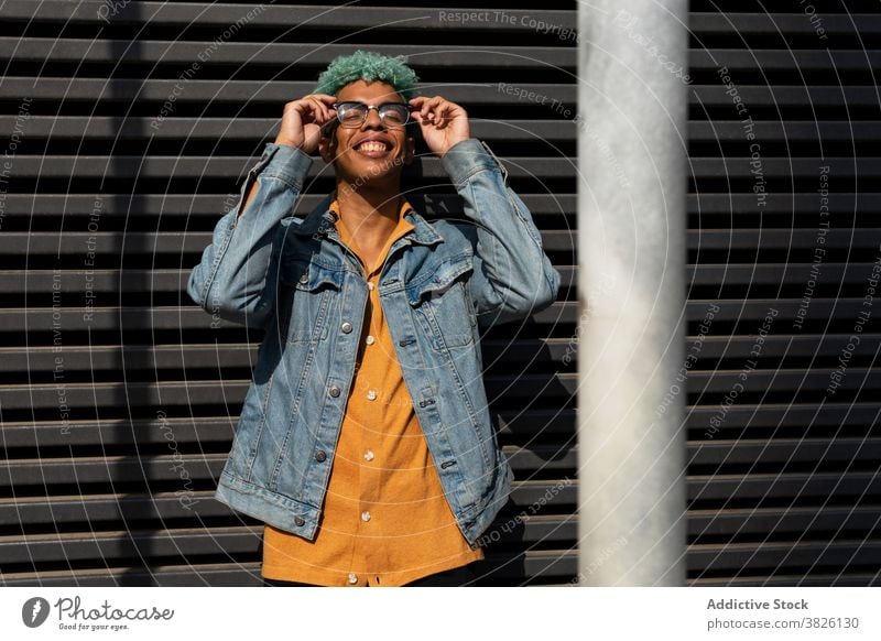 Trendy ethnic man on street in summer hipster blue hair eyeglasses put on style trendy generation male black african american sunny urban city enjoy young relax