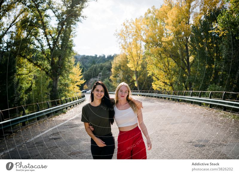 Happy female friends hugging on country road women forest autumn happy friendship countryside nature cheerful young roadway together girlfriend embrace smile