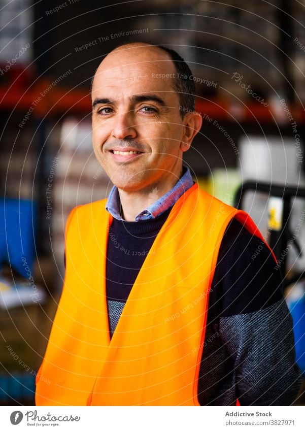 Male warehouse employee in uniform standing near rack in warehouse man happy worker smile professional at work storage storehouse workplace industry calm